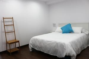 阿利坎特阿利坎特彩色套房公寓的一张带蓝色枕头和梯子的白色床