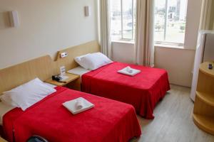 巴西利亚艾拉姆巴西利亚酒店的两张位于酒店客房的床铺,配有红色床单