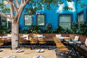 洛杉矶Palihotel Culver City的餐厅在蓝色的墙壁前设有桌椅