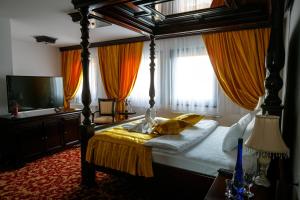 新瓦罗什Hotel Zlatarski Zlatnik的一间卧室配有带橙色窗帘的天蓬床