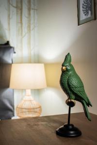 南特Maisons du Monde Hotel & Suites - Nantes的坐在台灯旁的绿鸟