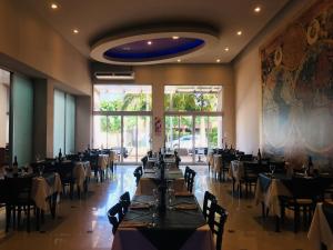 伊图萨因戈Atlas Grand Hotel Ituzaingo的一间带桌椅的用餐室和大窗户