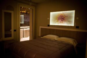 普拉托讷沃斯Hotel Laghetto的卧室配有一张床,墙上挂有绘画作品