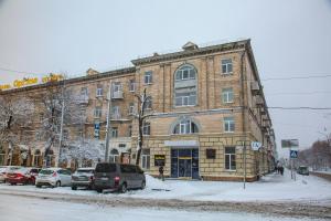 切尔卡瑟Optima Cherkasy Hotel的一座大型砖砌建筑,前面有汽车停放
