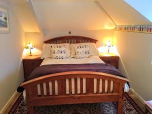 卡姆尔福德Culloden Farmhouse的一间卧室配有一张带两盏灯的大木床。