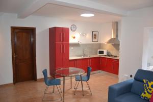 蒂亚斯Villa Jupe的厨房配有红色橱柜和玻璃桌椅