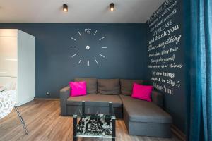 罗兹Apartament Manufaktura的客厅配有沙发和墙上的时钟