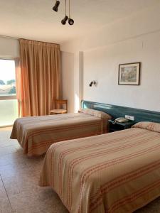 Villafranca de EbroHotel Pepa的酒店客房设有两张床和窗户。