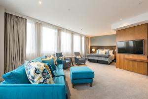 基督城基督城卓越酒店的一间带蓝色沙发的客厅和一间卧室