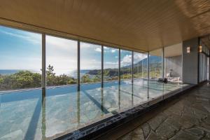 屋久岛samana hotel Yakushima的一座带玻璃窗户的游泳池的房子