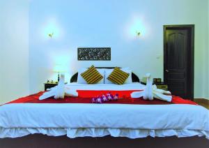 暹粒桑那龙精品度假村的卧室配有一张带白色床单和鲜花的大床