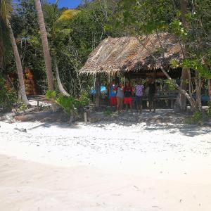 KriTurtle Dive Homestay的一群人站在海滩上的小屋里