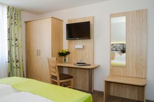 贝兴Hotel-Gasthof Blaue Traube e.K.的一间卧室配有一张床和一张书桌及电视
