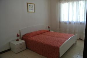 利尼亚诺萨比亚多罗Condominio LISA的一间卧室配有一张带红色床罩的床和窗户