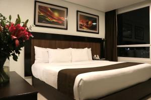 墨西哥城PF套房酒店的一间卧室配有一张大床和花瓶