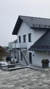 HepbachLUX Ferienwohnungen的停车场内有楼梯的白色房子