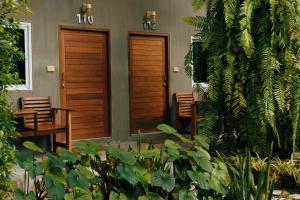 卡农佩斯度假村的两扇木门,位于一座植物繁茂的房屋的一侧