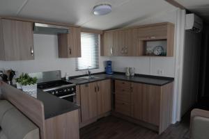 拉隆德莱丝莫里斯Camping Parcvalrose Mobile Home No 79的厨房配有木制橱柜和炉灶烤箱。