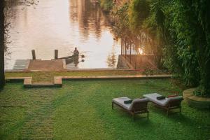 科钦Chittoor Kottaram Royal Mansion- CGH Earth的两把长椅坐在草地上,靠近水体