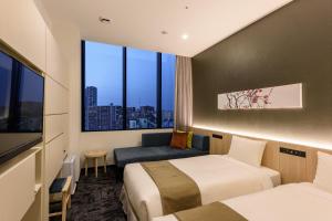 东京hotel MONday Premium TOYOSU的酒店客房设有两张床和窗户。