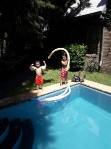 罗萨里奥La casa de Hostal del Sol的两个男孩在游泳池里玩飞盘
