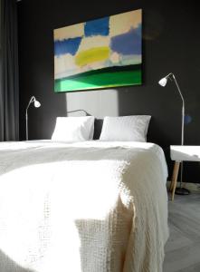 吕伐登Hus的卧室配有一张带两盏灯的白色床和一幅画