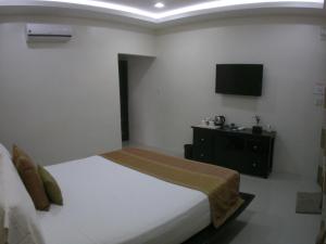奥斯洛布AJ's Place Beach Resort的卧室配有一张床,墙上配有电视。