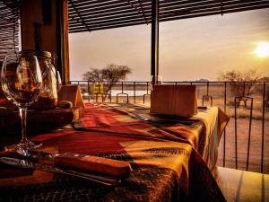 OkazizeOvita Wildlife Restcamp的一张带葡萄酒玻璃的桌子和一个美景窗户