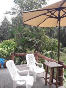 阁帕延岛JJ海滩与海鲜度假酒店的天井上配有一张桌子和两把椅子以及一把遮阳伞。