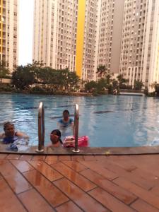 贝克西Apartemen Springlake Summarecon Bekasi-By Bu Johan的城市游泳池的三人