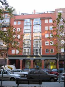 马德里Ribera的一座红色的大建筑,停车场有汽车停放