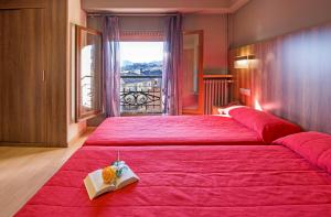 塞奥-德乌赫尔大道酒店的一间卧室配有一张红色大床,上面有书
