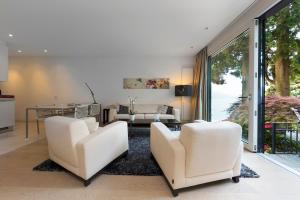 卢加诺紫罗兰花园公寓的客厅配有2把白色椅子和桌子