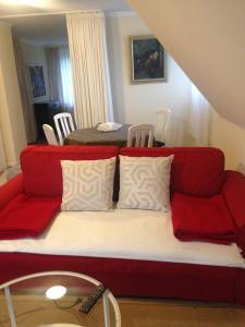 杜塞尔多夫Düsseldorf Messe -Apartment Milan的客厅里一张红色的沙发,配有桌子