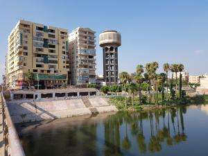 曼苏拉Al Mansoura Apartment的水体,有建筑物和钟楼