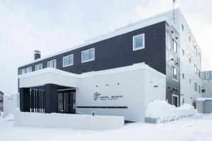 富良野Hotel Munin Furano的雪中黑白的建筑