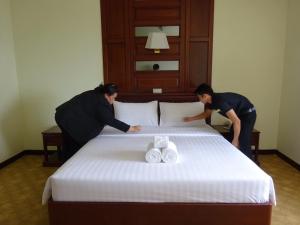 曼谷MIDO Hotel的两人在酒店房间准备一张床
