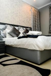 德班Tudor House Hotel的卧室配有一张带白色床单和枕头的大床。