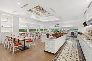 雅加达雅加达雅诗阁住宅酒店的餐厅设有白色的柜台和桌椅