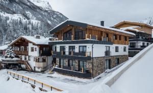 索尔登A CASA Rubin Chalet & Studio Resort的一座雪地中的建筑,背景是一座山