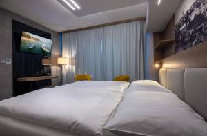 恰斯拉夫Hotel Grand的酒店客房设有一张白色大床和电视。