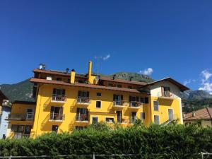 科马诺泰梅Hotel Posta的黄色的公寓大楼,背景是群山