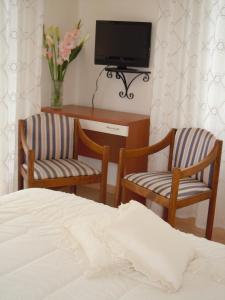 塔皮安诺Albergo Elvira的一间卧室配有两把椅子、一台电视和一张床