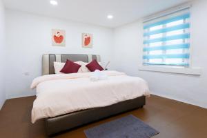 马六甲Jia Residence的一间卧室配有一张带红色枕头的床和一扇窗户