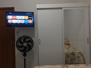阿雷格里港Próximo à ACISP, APM, PUC e UFRGS的卧室配有风扇和墙上的电视。