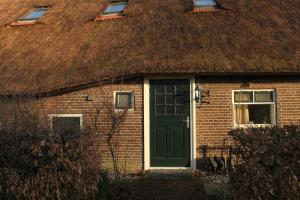 希尔登B&B De Rumelshof的茅草屋顶的房屋,设有绿门