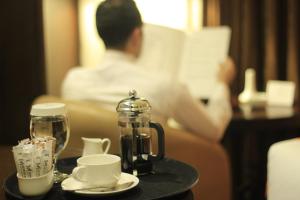 安曼梅内尔酒店的在酒店房间阅读书籍的人,房间内设有咖啡机