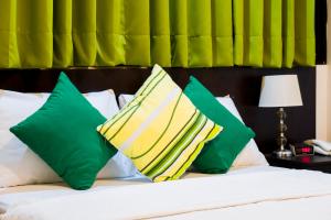 塔拉波托Hotel Fatima Inn的一张带绿色和黄色枕头的床