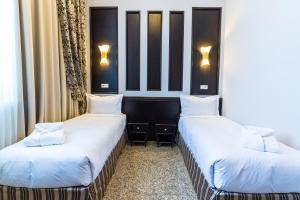 塔尔迪库尔干Royal Petrol Hotel的配有白色床单的酒店客房内的两张床
