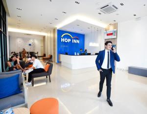 马尼拉Hop Inn Hotel Tomas Morato Quezon City的穿着西装的人在大堂的电话里说话